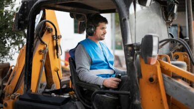 Worker operating excavator with safety gear