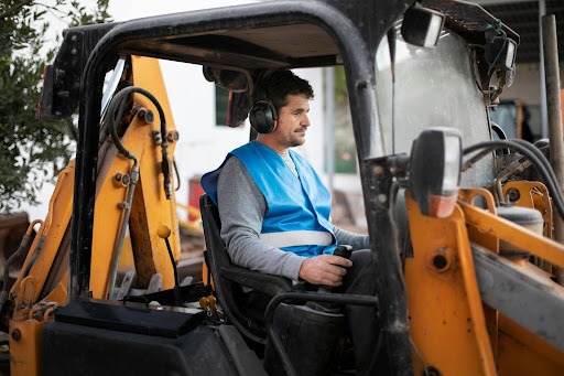 Worker operating excavator with safety gear